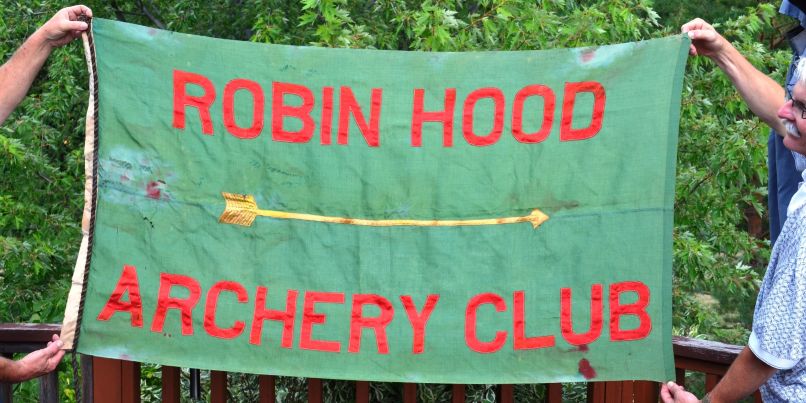 Members holding up the green Robin Hood Archery Club banner