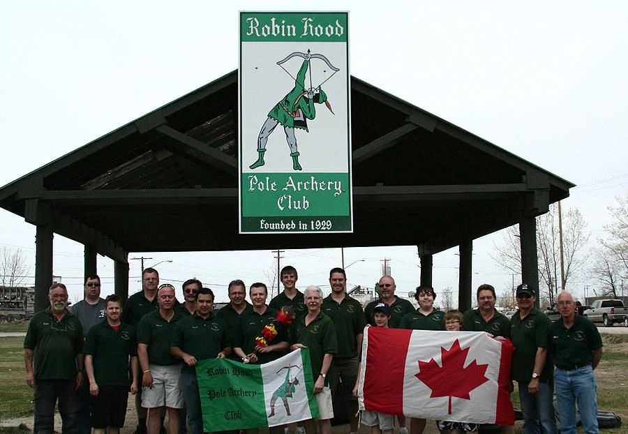 Members of the Robin Hood Pole Archery Club gathered under the club pavilion with the Canadian flag and the club flag