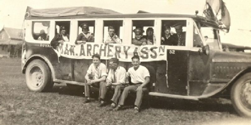 Members seated on a bus decorated with an archery association banner
