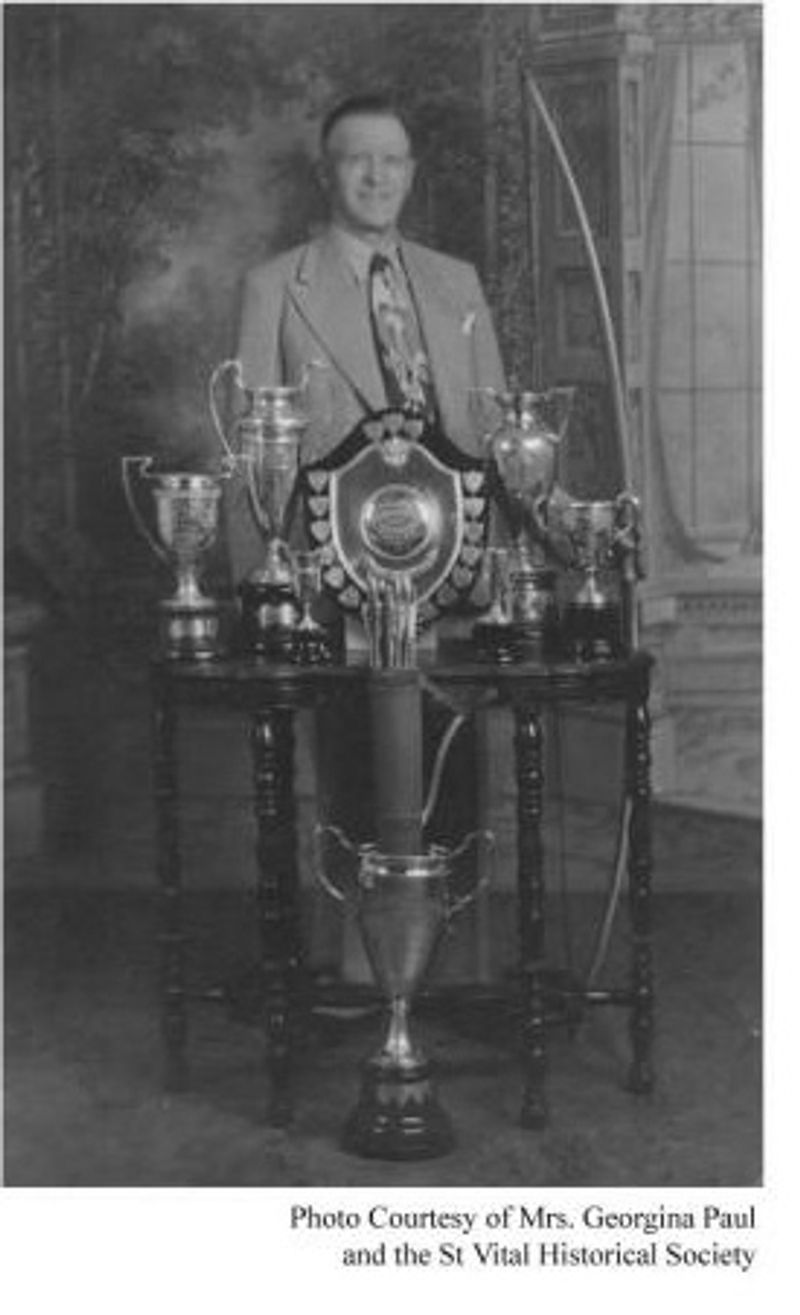Black-and-white portrait of a man seated behind a display of trophies