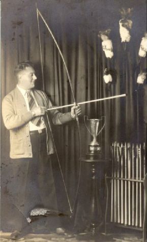Joe Verschaere holding a bow beside a trophy