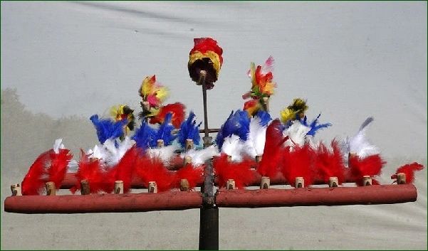 A close-up of the fork covered in red, white and blue feathered birds against a grey sky